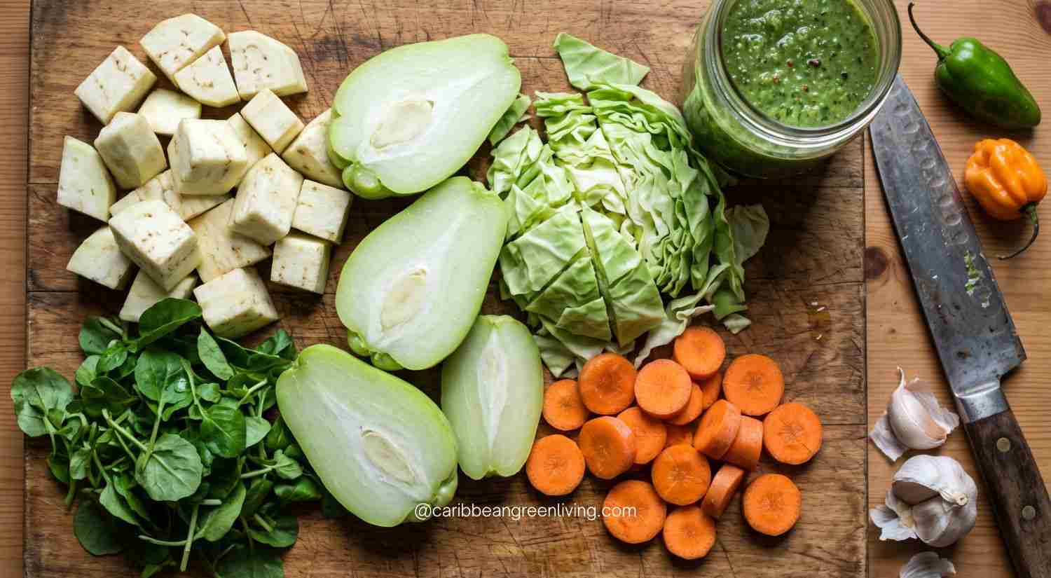 Mastering Haitian Legume (Légim): The Ultimate Guide to Depth, Texture, and Flavor 3 Prepped ingredients for Haitian legume on a wooden board including peeled eggplant, halved chayote, sliced carrots, cabbage, watercress, and epis.