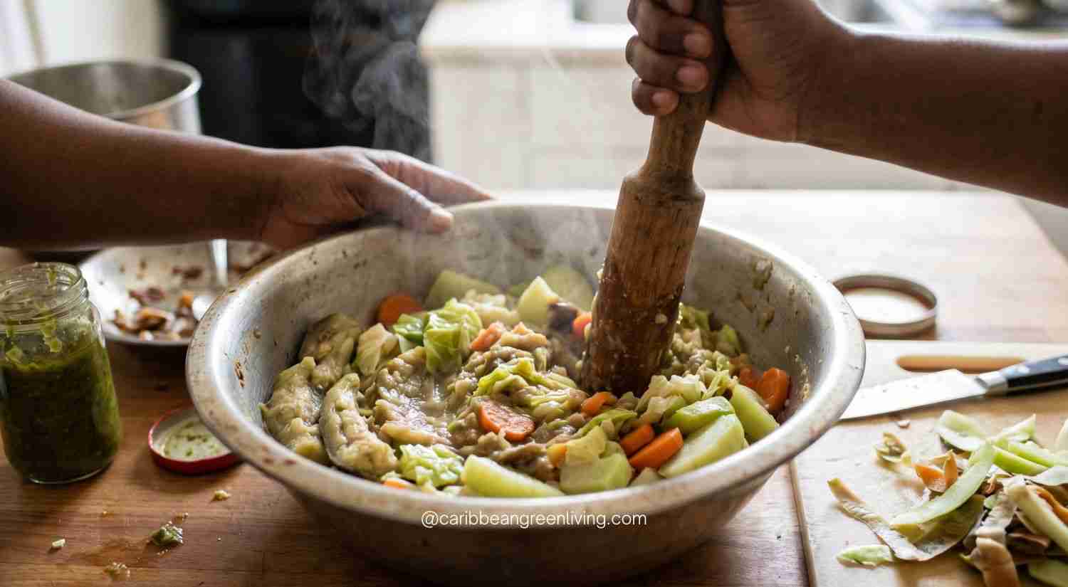 Mastering Haitian Legume (Légim): The Ultimate Guide to Depth, Texture, and Flavor 5 Mashing tender steamed eggplant, chayote, and cabbage in a metal bowl using a traditional wooden pestle for Haitian legume.
